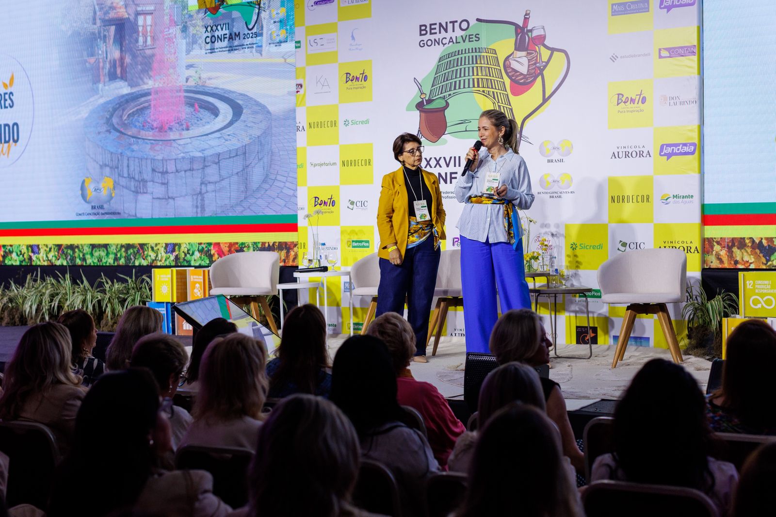 Rejane Duarte no palco ao lado de outra participante em evento associativo