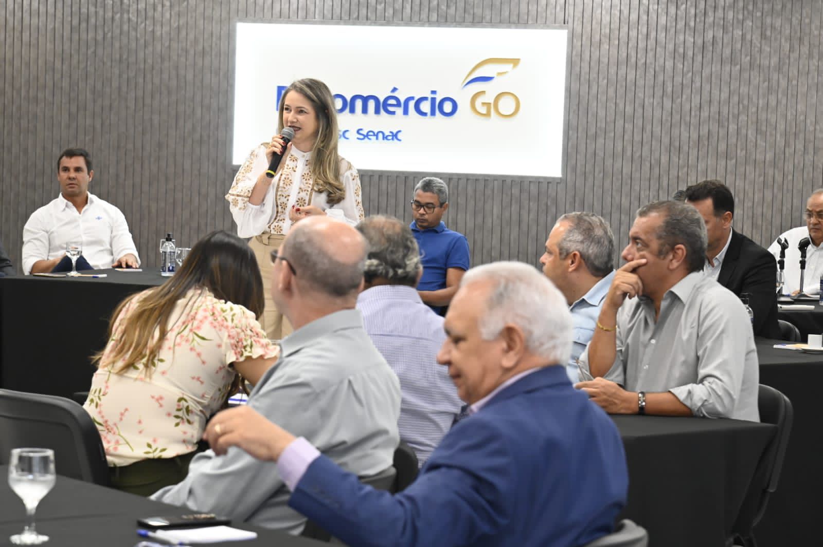 Rejane Duarte falando ao microfone em reunião na Fecomércio