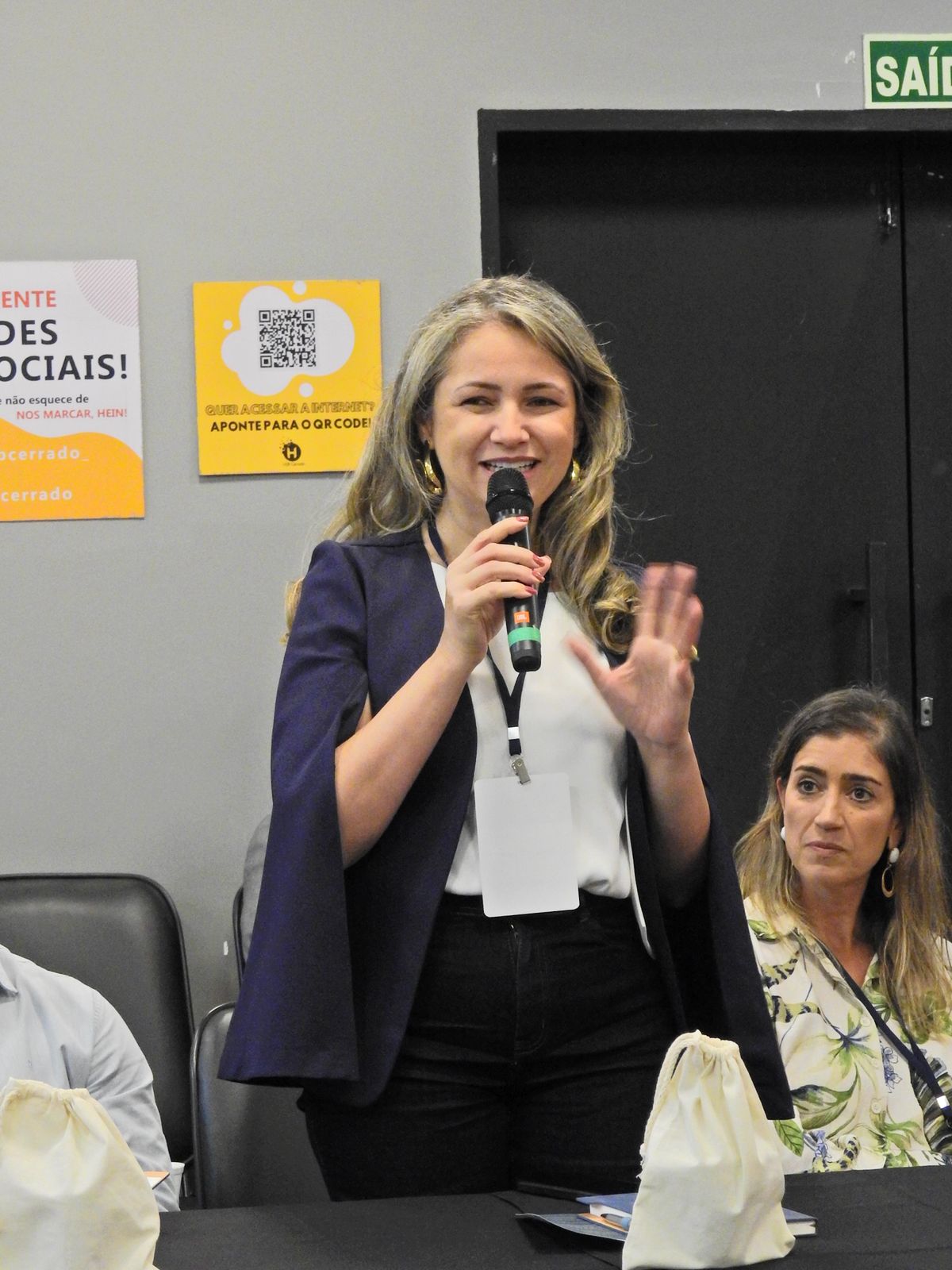 Rejane Duarte participando de discussão com microfone em ambiente institucional
