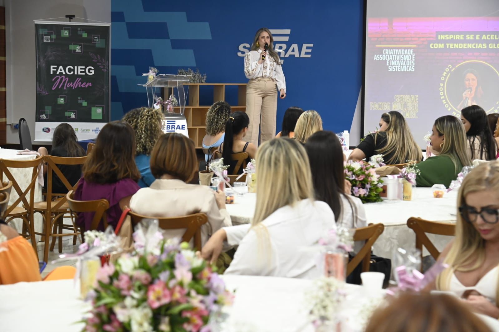 Rejane Duarte conduzindo palestra diante de um auditório