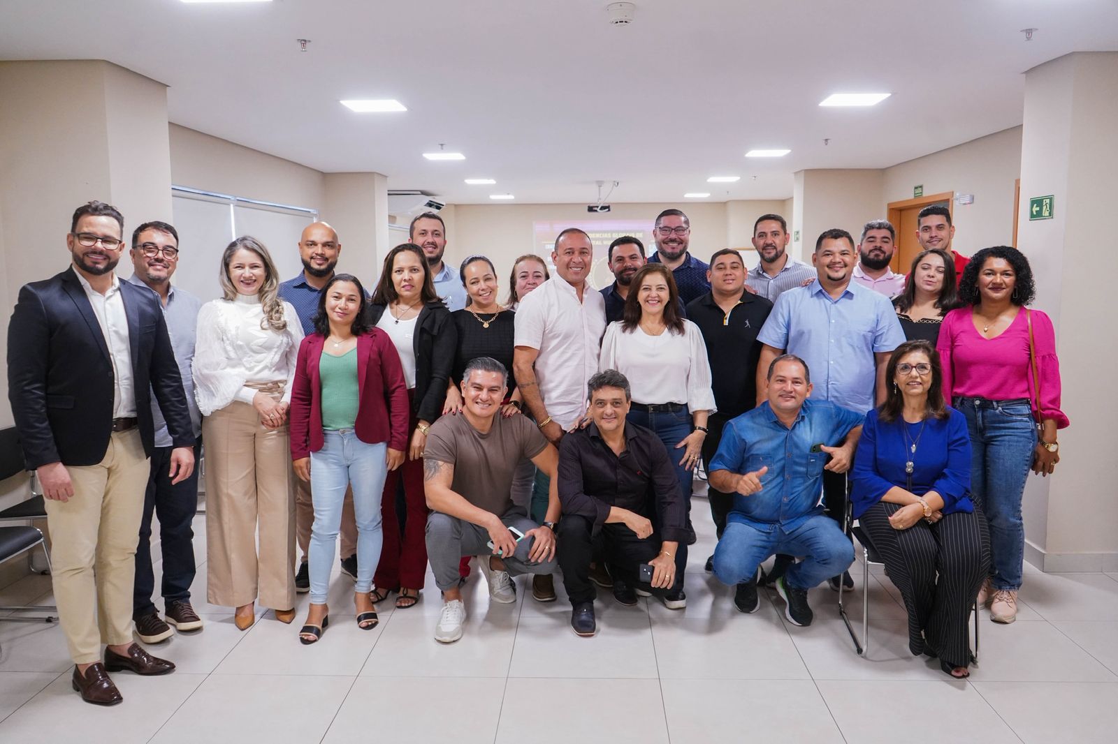 Rejane Duarte em reunião de gestão com equipe ao redor da mesa, em formato híbrido